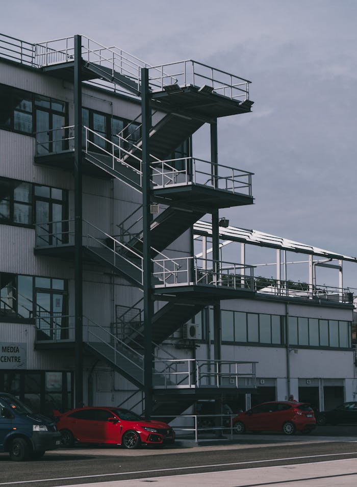Crafting Captivating Headlines: Your awesome post title goes here Exterior view of a modern industrial building with a steel staircase and parked cars in Mogyoród, Hungary.